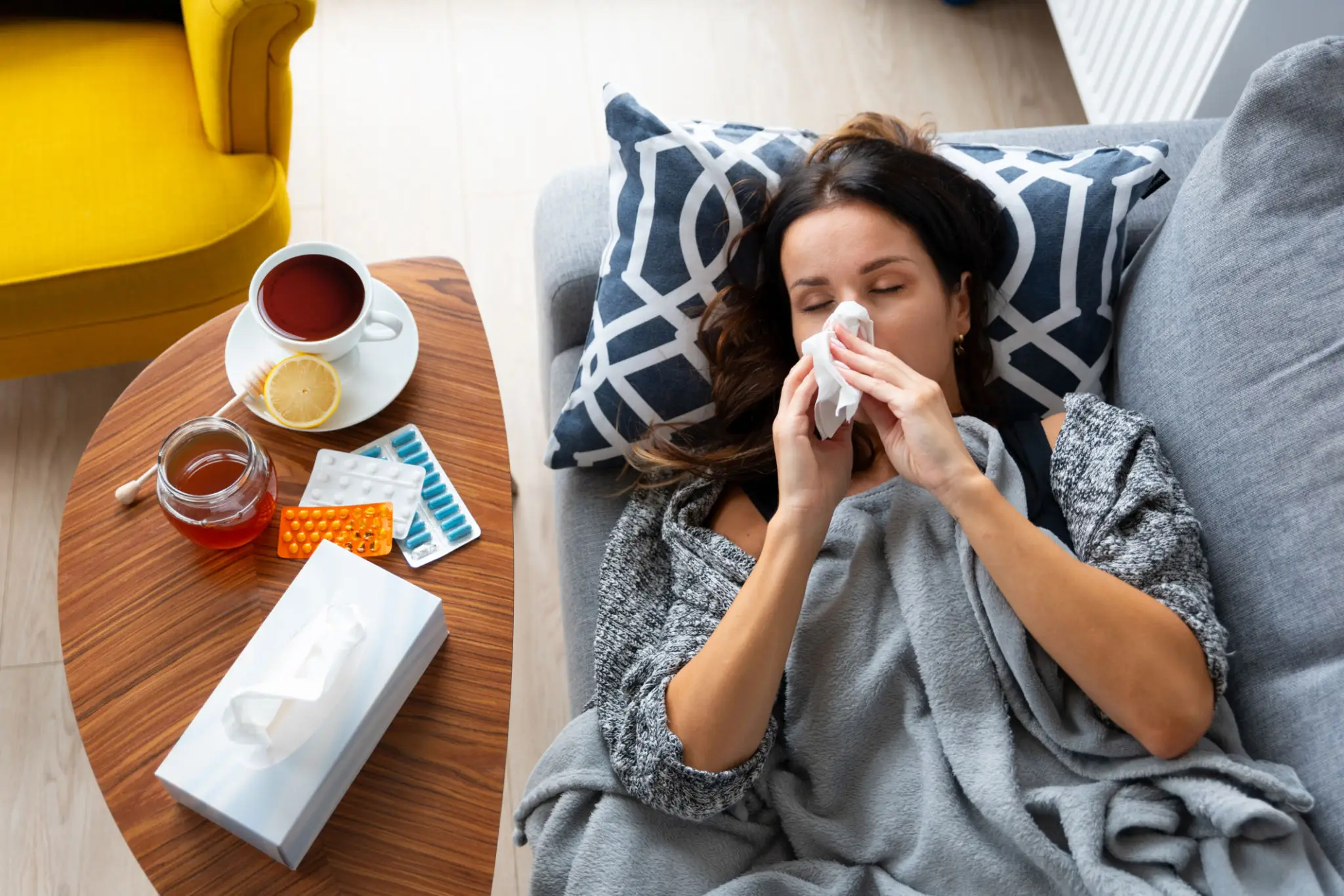 Sick woman blowing nose on couch