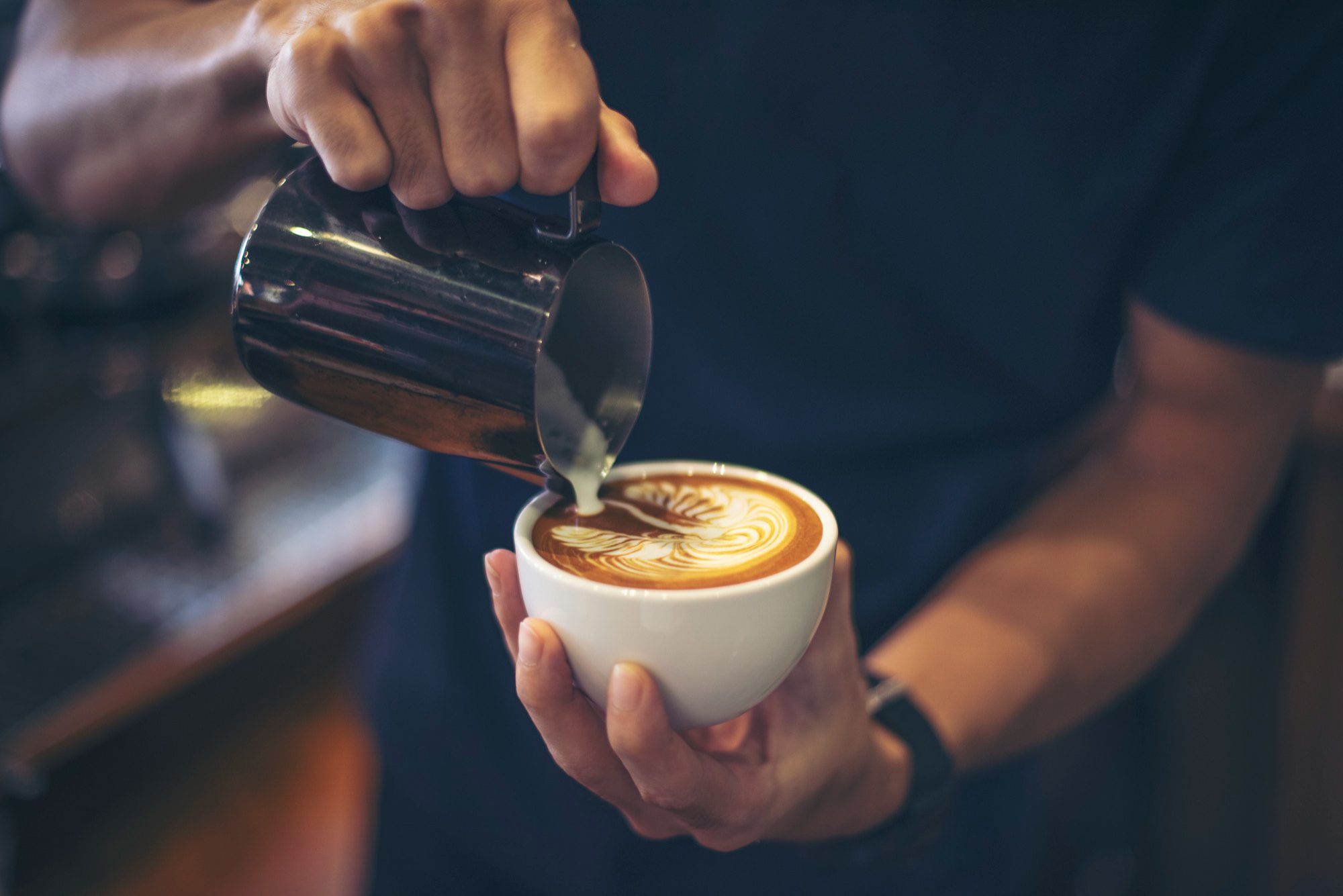 Barista pouring steamed milk creating latte art