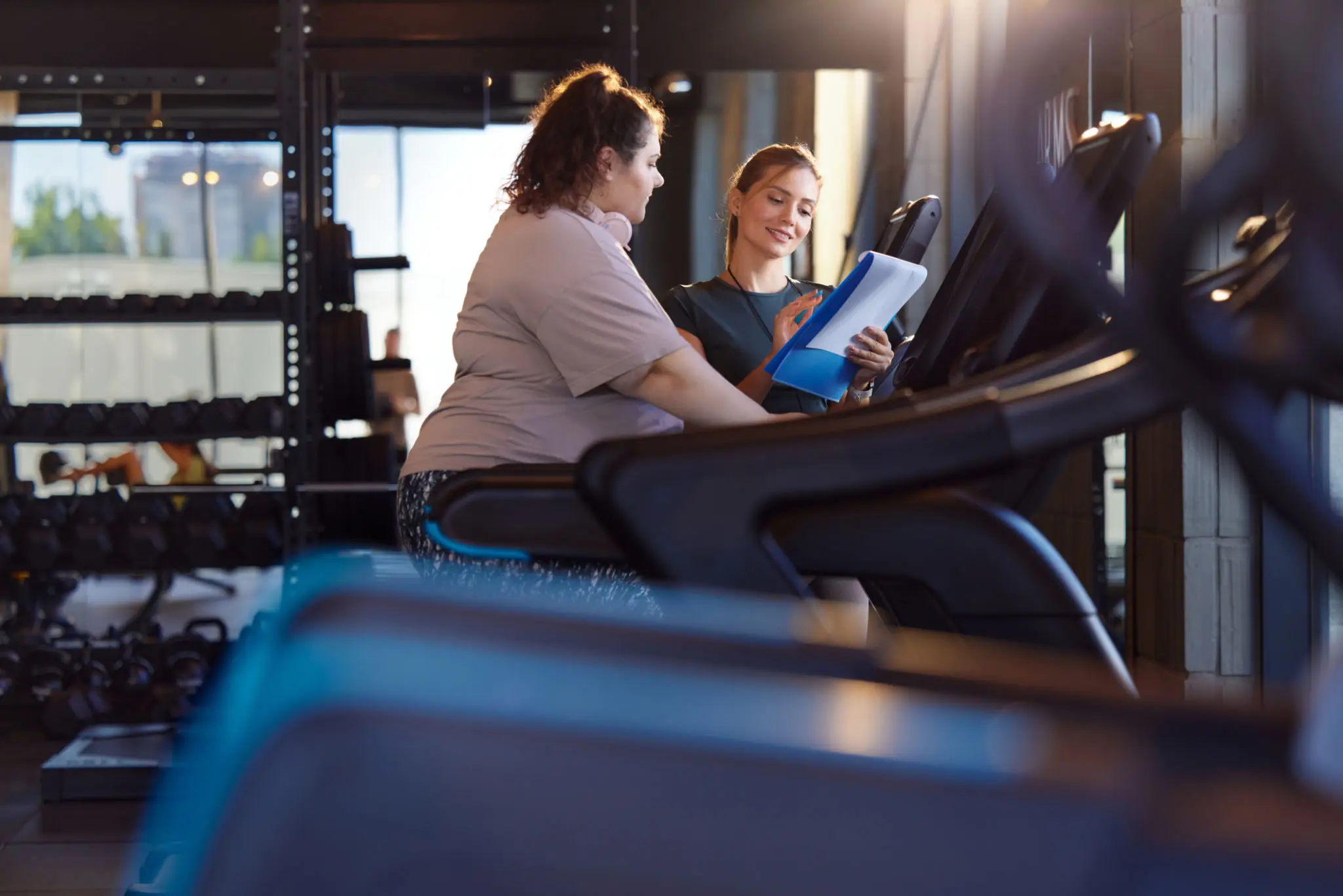 Trainer consulting client with clipboard at gym